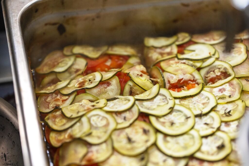a metal pan filled with sliced zucchini and tomatoes