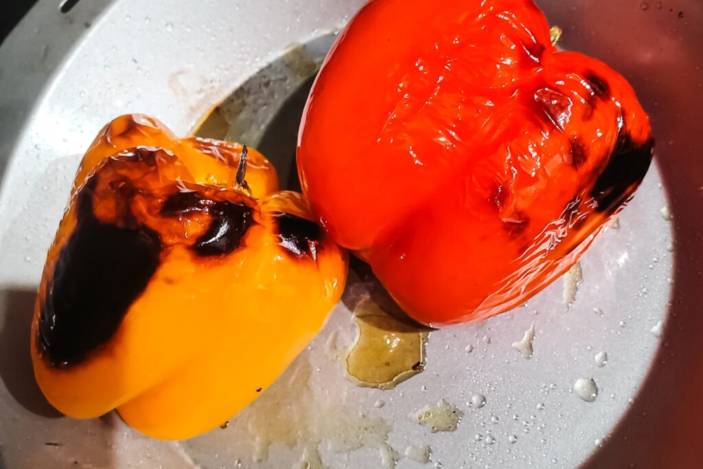 The image shows roasted bell peppers, their skins charred and blistered from high-heat cooking.